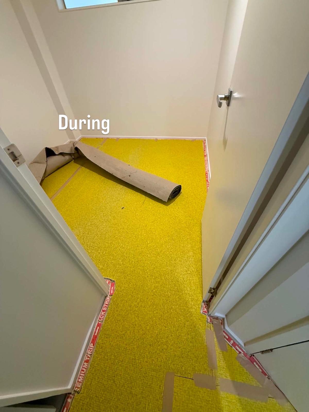 Yellow underlay and red smoothedge tack strips laid in the cupboard with a roll of carpet ready