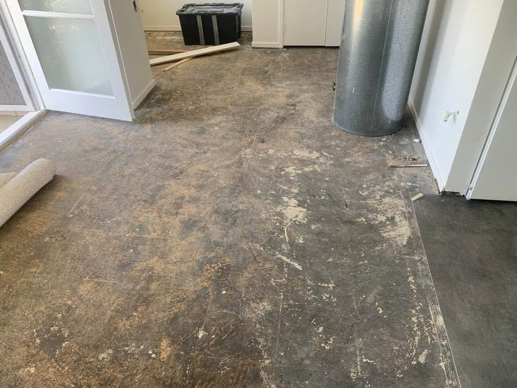Room stripped back to bare concrete subfloor with old carpet removed, ready for restoration